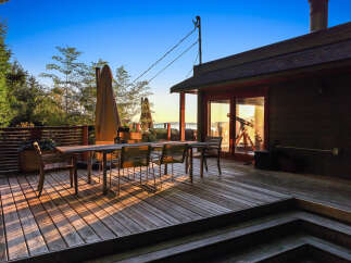 Enjoy breathtaking sunset views from this expansive wooden deck, perfect for outdoor dining and entertaining.