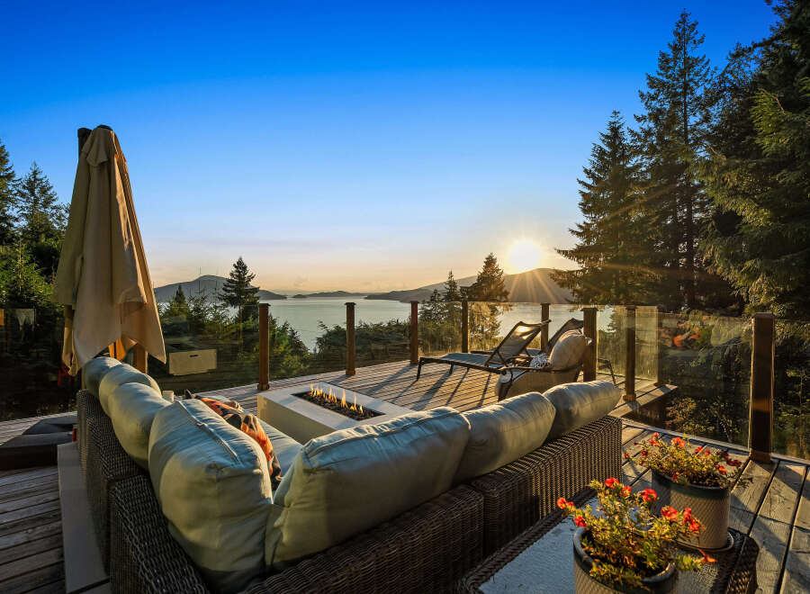 Experience breathtaking sunset views from this stunning deck, complete with a modern fire pit and comfortable seating.