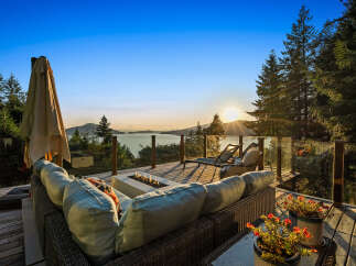Experience breathtaking sunset views from this stunning deck, complete with a modern fire pit and comfortable seating.