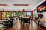 Experience breathtaking natural beauty from this stunning living and dining area, featuring expansive windows that frame panoramic views of lush greenery and serene waters.