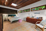 Experience a unique bedroom retreat featuring a stunning wood-paneled ceiling with a skylight, complemented by a dark wood accent wall behind the bed.