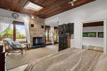 Experience luxurious living in this stunning bedroom featuring a cozy fireplace with a stone accent wall and a skylight for natural light.