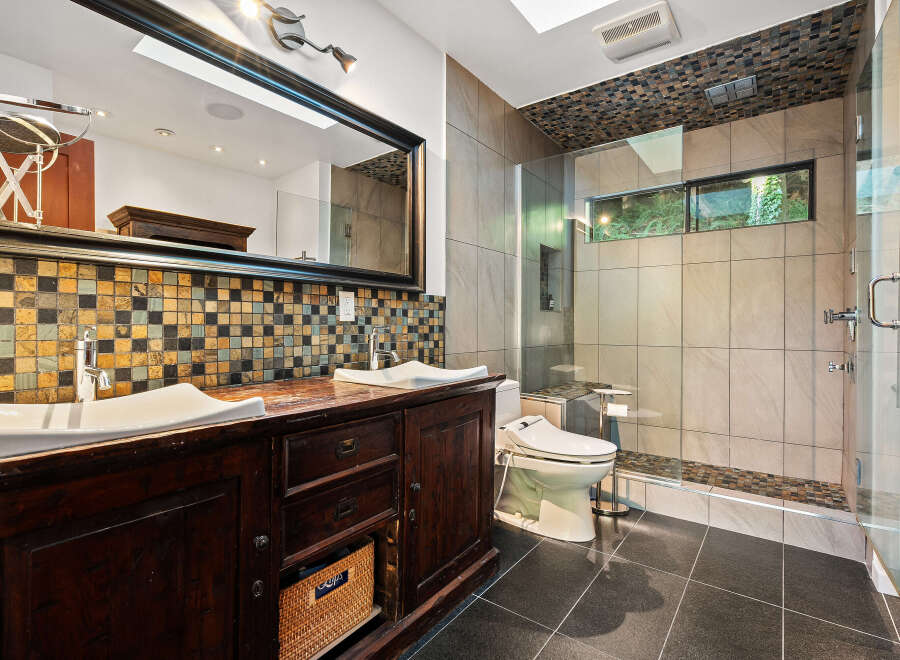 Experience luxury in this modern bathroom featuring a spacious double vanity with a mosaic tile backsplash and elegant vessel sinks.