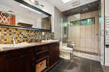 Experience luxury in this modern bathroom featuring a spacious double vanity with a mosaic tile backsplash and elegant vessel sinks.