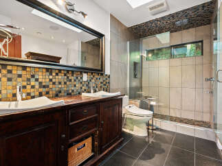 Experience luxury in this modern bathroom featuring a spacious double vanity with a mosaic tile backsplash and elegant vessel sinks.