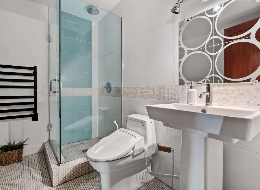 Experience modern luxury in this stunning bathroom, featuring a sleek glass-enclosed shower with soothing blue tiles and a convenient bidet toilet.