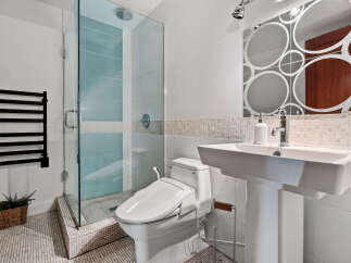 Experience modern luxury in this stunning bathroom, featuring a sleek glass-enclosed shower with soothing blue tiles and a convenient bidet toilet.