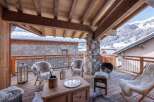 Experience luxurious mountain living on this stunning wooden balcony, complete with plush, fur-covered seating and a cozy fire pit.
