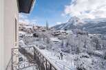 Experience the magic of a winter wonderland from your private balcony, offering breathtaking panoramic views of a snow-covered village nestled in the Alps.