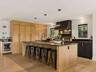 Experience luxury in this stunning modern kitchen, featuring sleek custom wood cabinetry and a large central island with a waterfall countertop.