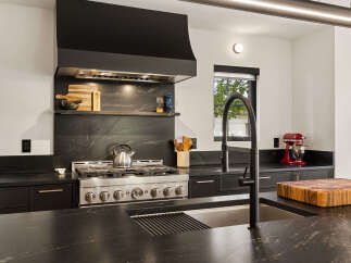 Experience culinary excellence in this modern kitchen, featuring a sleek black granite countertop and backsplash.