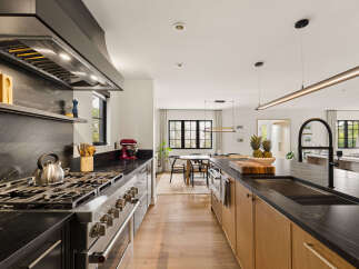Experience luxury in this modern kitchen featuring a professional-grade gas range and a sleek, dark stone backsplash.