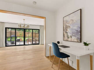 This modern home features a bright and airy open-concept living space with a sleek white desk and a comfortable blue chair, perfect for a home office setup.