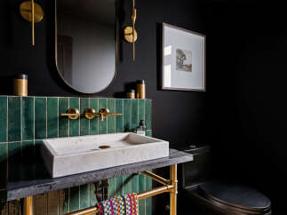 This modern powder room features a striking dark aesthetic, enhanced by a bold green tiled backsplash behind a sleek marble vessel sink.