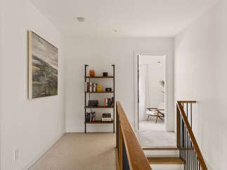 Ascend to the upper level of this home via a stylish staircase featuring a warm wood handrail and sleek black balusters.