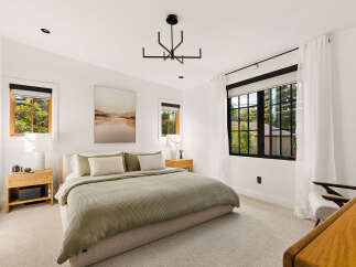Experience serene living in this beautifully appointed bedroom, featuring a plush king-sized bed adorned with soft, neutral-toned linens and accent pillows.
