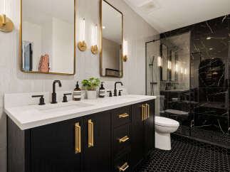 Experience modern luxury in this stunning bathroom featuring a sleek black vanity with gold hardware and a quartz countertop.
