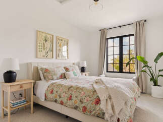 This serene bedroom features a plush upholstered bed adorned with a botanical print duvet and a cozy knit throw.