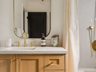 Experience modern luxury in this beautifully appointed bathroom, featuring a sleek vanity with warm wood cabinetry and elegant brass fixtures.