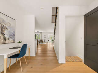 Discover modern living in this beautifully appointed home featuring a dedicated workspace with a stylish blue chair and a laptop, perfect for remote work.