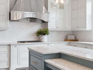 Experience luxury in this stunning kitchen featuring a sleek stainless steel range hood and a beautiful herringbone tile backsplash.