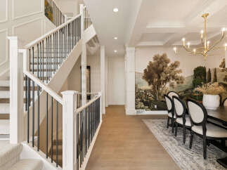Experience luxury living in this stunning home featuring an elegant staircase with intricate molding and a sophisticated dining area.