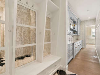 This elegant mudroom features mirrored cabinet doors with a distressed finish, providing a touch of vintage charm.