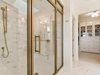 Experience luxury in this stunning bathroom featuring a spacious walk-in shower with elegant marble tile and a convenient handheld showerhead.