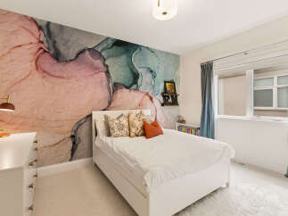 This charming bedroom features a stunning abstract art wallpaper accent wall, creating a unique and artistic focal point.