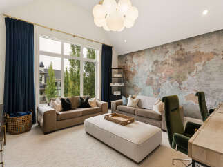 Experience luxury living in this stunning room featuring a world map accent wall and a large picturesque window overlooking lush greenery.