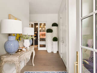 Step into this elegant entryway featuring a charming console table adorned with decorative lamps and floral arrangements.