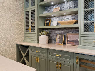 This custom built-in cabinetry features a sophisticated sage green finish, complemented by elegant gold hardware.