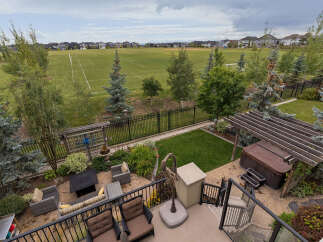 Enjoy outdoor living with this stunning backyard featuring a spacious patio, a relaxing hot tub under a pergola, and a lush green lawn perfect for recreation.