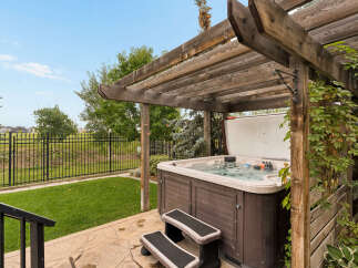 Enjoy ultimate relaxation in this backyard oasis, featuring a spacious hot tub nestled under a charming wooden pergola.
