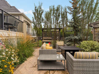 Enjoy outdoor living in this beautifully landscaped backyard featuring a spacious patio with comfortable wicker furniture and a fire pit.