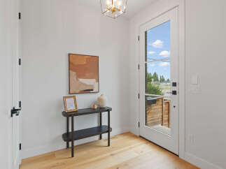 Step into this inviting entryway featuring a sleek console table adorned with decorative pieces and a striking abstract artwork.