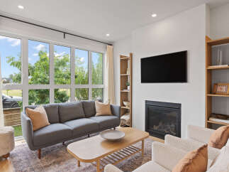 Experience modern living in this bright and airy living room, featuring a sleek gas fireplace and a large window with scenic views.