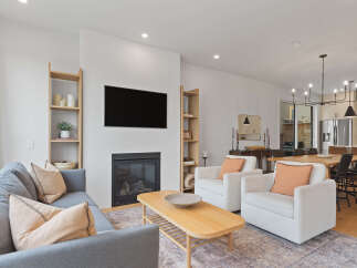 Experience modern living in this open-concept space featuring a cozy living area with a fireplace and a mounted TV, perfect for relaxation.