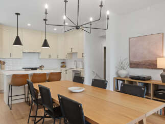This modern dining area features a sleek, light wood dining table paired with black upholstered chairs, perfect for intimate gatherings.