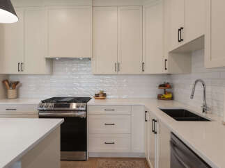 Experience modern living in this stunning kitchen featuring sleek, cream-colored cabinetry with black hardware.