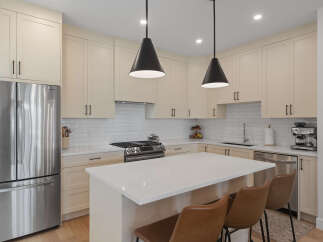 Experience modern living in this stunning kitchen featuring sleek, cream-colored cabinetry and a spacious quartz island perfect for meal prep and entertaining.