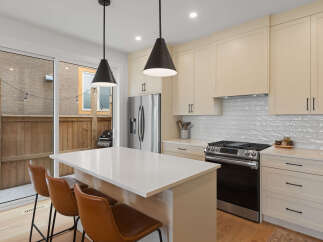 Experience modern living in this stunning kitchen featuring sleek cream cabinetry and a spacious quartz island perfect for casual dining or entertaining.