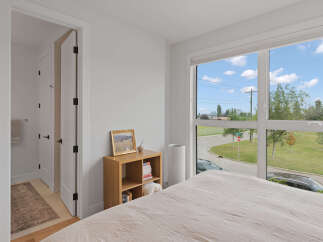 Experience modern living in this bright bedroom featuring a large window with scenic views of the neighborhood.