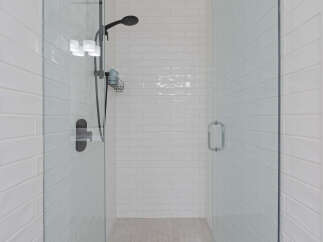 Step into this modern shower featuring sleek white subway tiles and a convenient glass enclosure.
