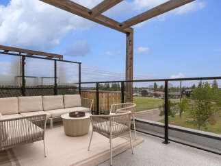 Enjoy breathtaking views from this modern rooftop patio, featuring a comfortable sectional sofa and two accent chairs perfect for outdoor entertaining.