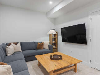 This modern living room features a comfortable sectional sofa adorned with plush throw pillows and a cozy blanket, perfect for relaxing evenings.