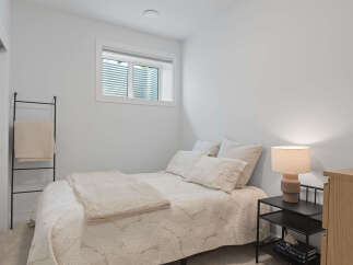 Discover comfort and style in this inviting bedroom, featuring a plush queen-size bed adorned with soft, textured linens and decorative pillows.