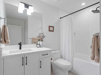 This modern bathroom features a sleek white vanity with black hardware, complemented by a black faucet and a large mirror.