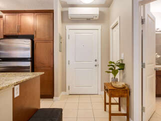 Step into this inviting entryway featuring a sleek stainless steel refrigerator and ample cabinet space, perfect for a modern kitchen.