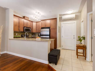 This modern condo features a sleek kitchen with rich wood cabinetry, granite countertops, and stainless steel appliances, perfect for any home chef.